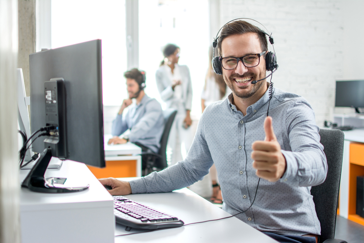 Happy male customer service operator showing thumb up in office.